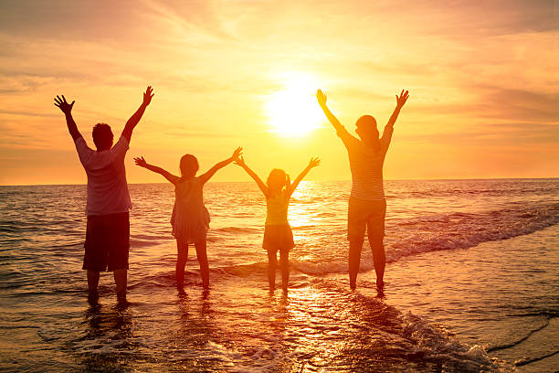 Une famille lève les bras face au soleil